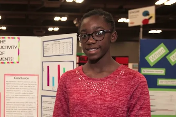 A young girl in front of her science project.
