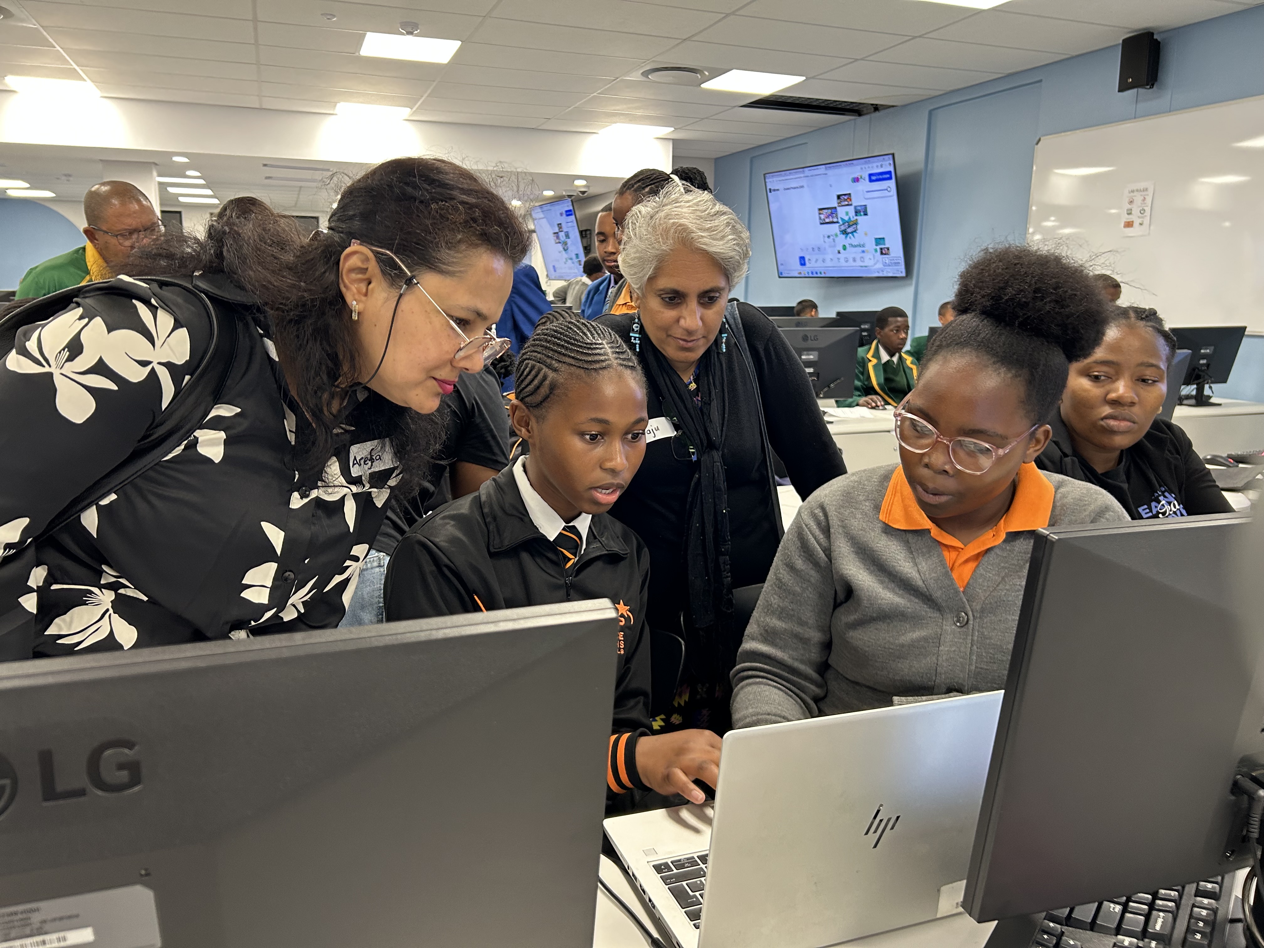 Two young people show their computer project to two adult judges.