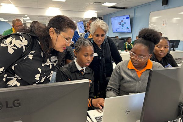 Two young people show their computer project to two adult judges.