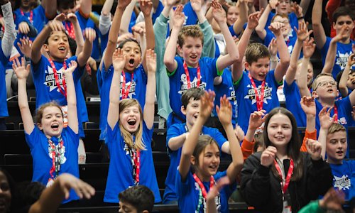 A large group of young people laughing and waving.