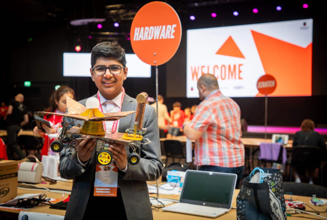 A young creator holding up their hardware creation at Coolest Projects UK 2024.