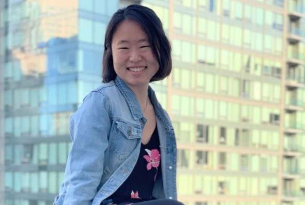 Coolest Projects participant sits on wall against the backdrop of skyscrapers 