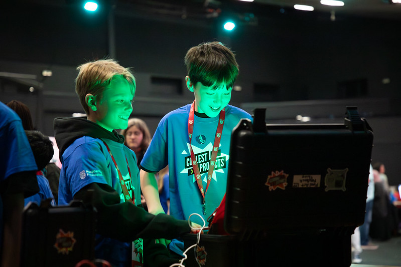 Two boys look at a computer screen, with green light shining onto their faces.