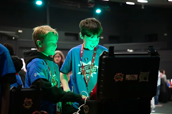 Two boys look at a computer screen, with green light shining onto their faces.