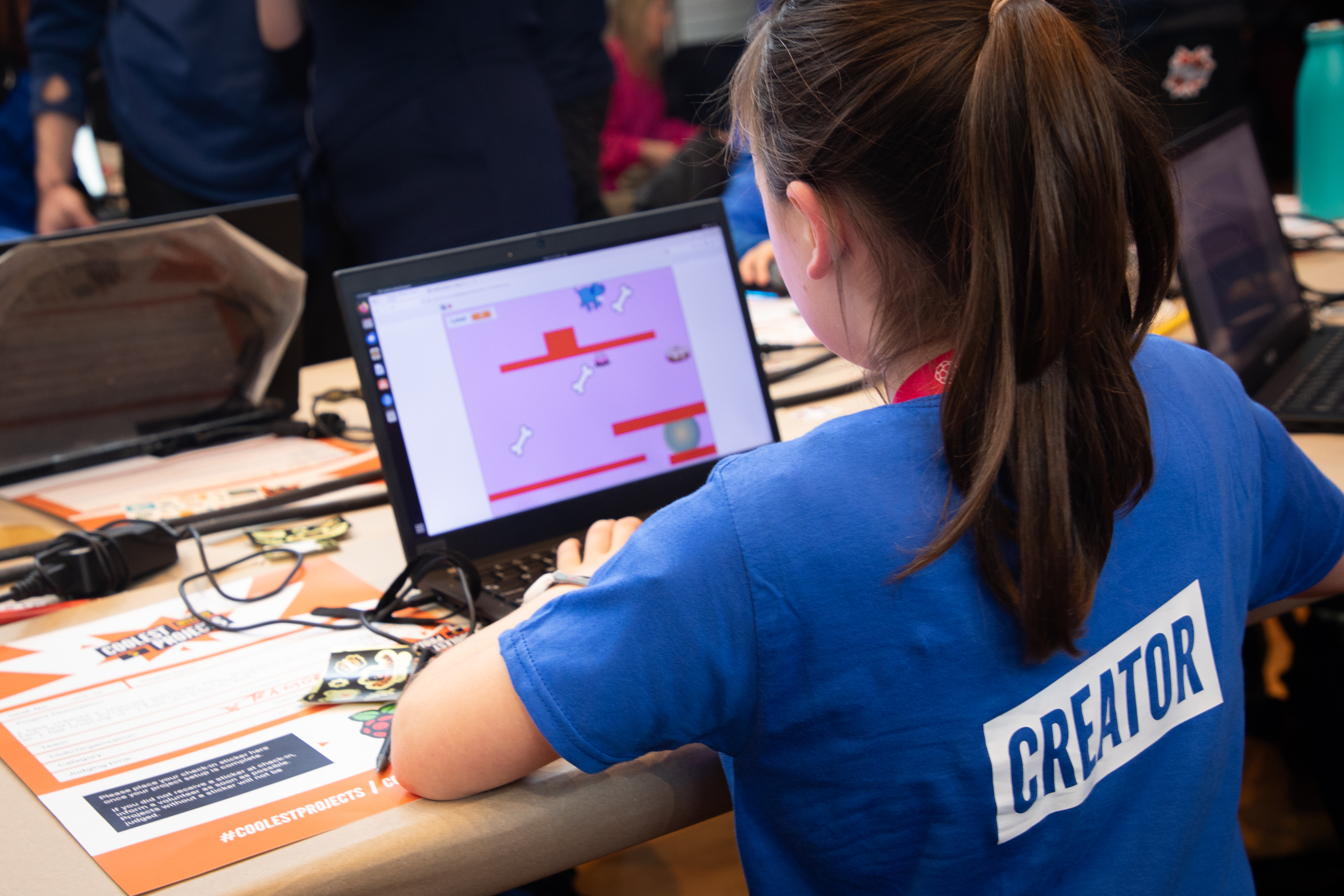 A young creator playing a game on a laptop at a Coolest Projects event