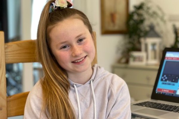 Young tech creator sat by her laptop with her coding project