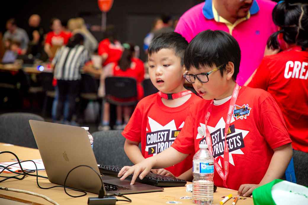 Two young participants using a laptop at a live Coolest Projects event