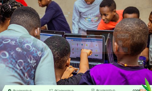 A group of young people look at a laptop.