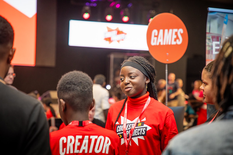 Two young people talking at a busy event.