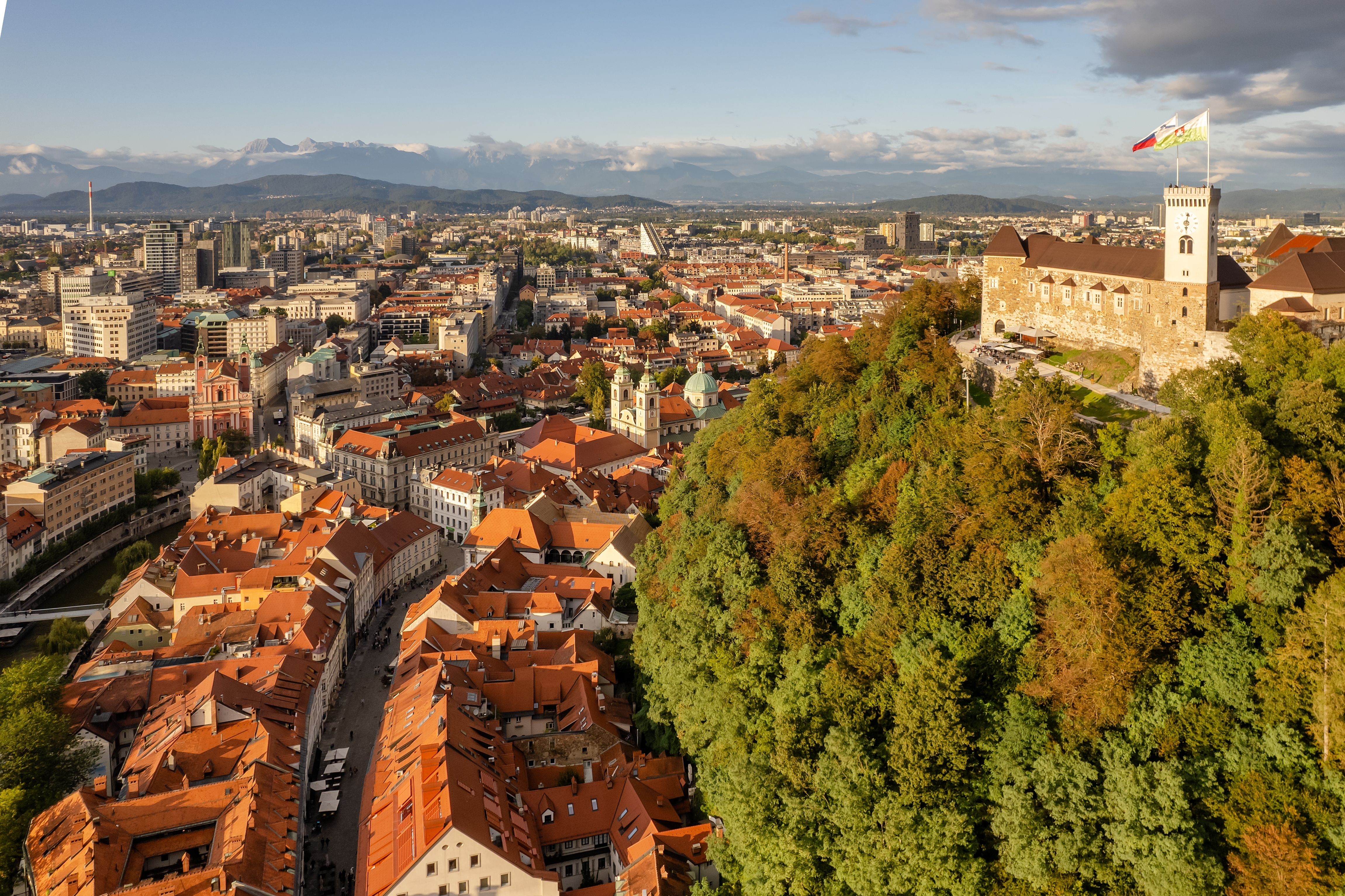 Evaluating The Cost-Benefit Analysis of Climate Adaptation Measures From An Insurance Perspective _ Aerial view of the Ljubljana old town, Slovenia. Ljubljana castle, historic buildings and Ljubljanica river in Slovenian capital at sunny day. Beautiful mountain range at background 