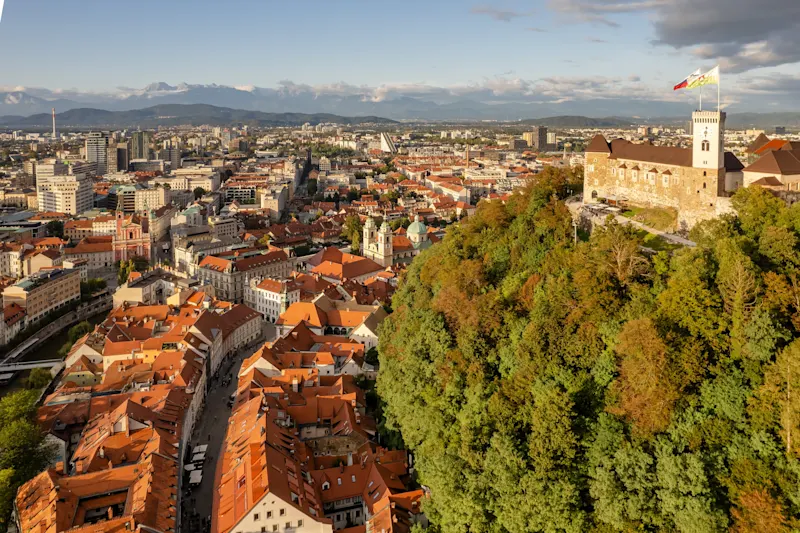 Evaluating The Cost-Benefit Analysis of Climate Adaptation Measures From An Insurance Perspective _ Aerial view of the Ljubljana old town, Slovenia. Ljubljana castle, historic buildings and Ljubljanica river in Slovenian capital at sunny day. Beautiful mountain range at background 