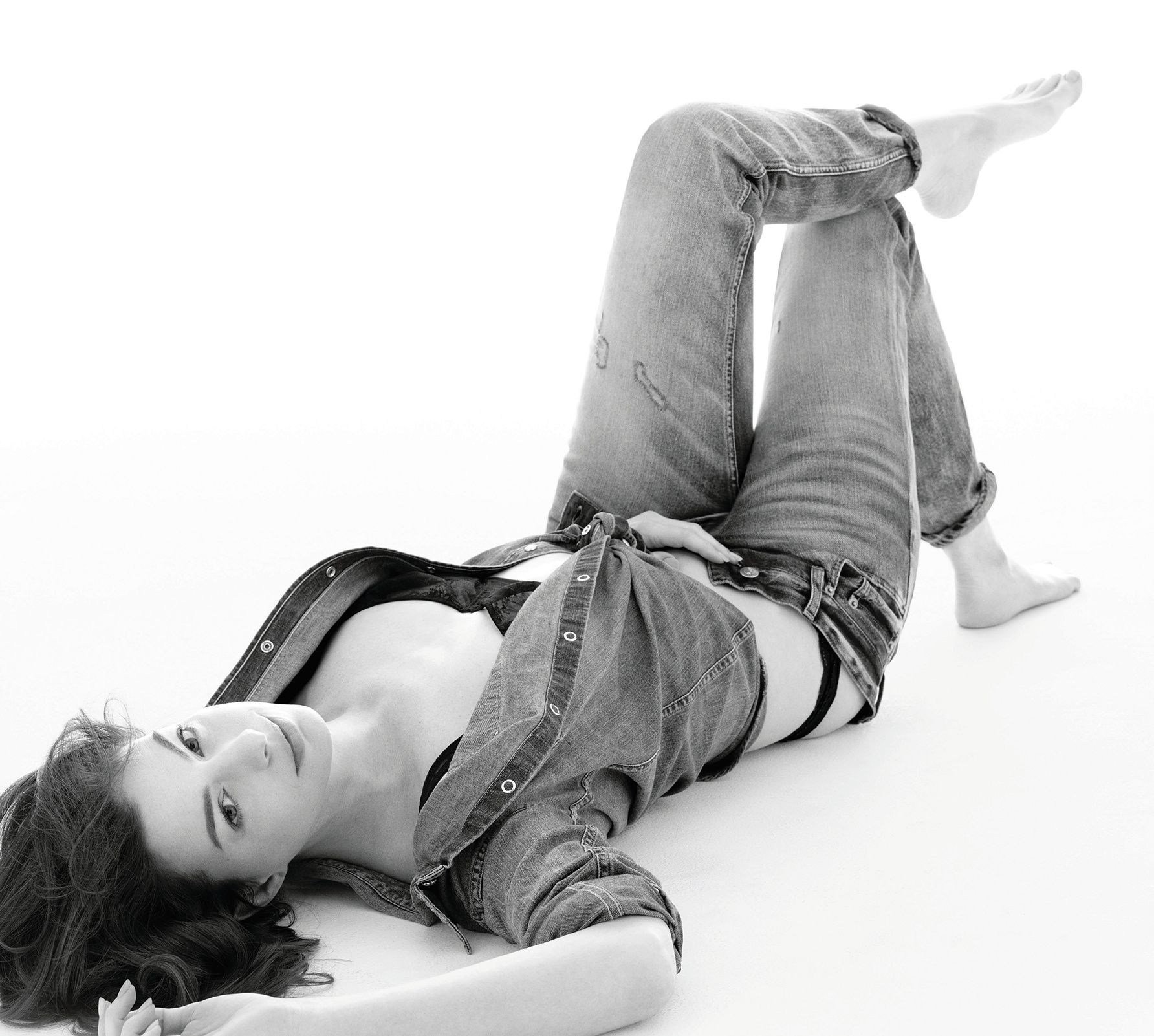 Anne Hathaway in double denim, lying on her back on the floor.