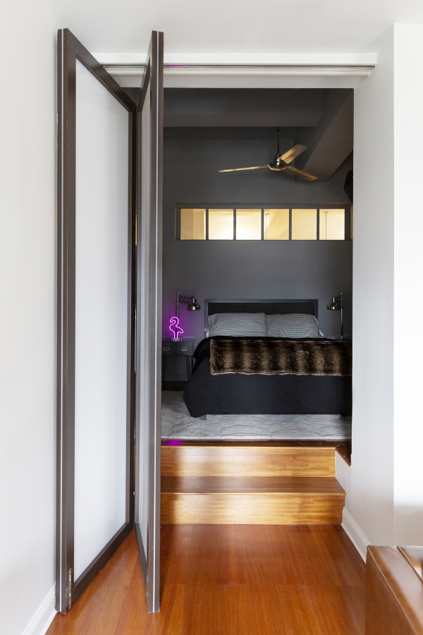 Hell's Kitchen Loft residential interior design by Basicspace. Folding door that steps up into the bedroom.
