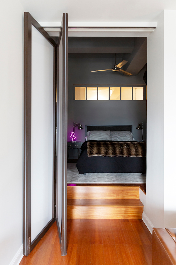 Hell's Kitchen Loft residential interior design by Basicspace. Folding door that steps up into the bedroom.