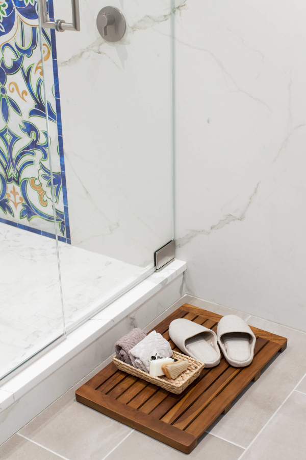 Park Slope Brownstone bathroom residential interior design renovation by Basicspace. Detail of frameless shower glass door, marble and floor tile. Slippers, wooden bath mat complete the bathroom.