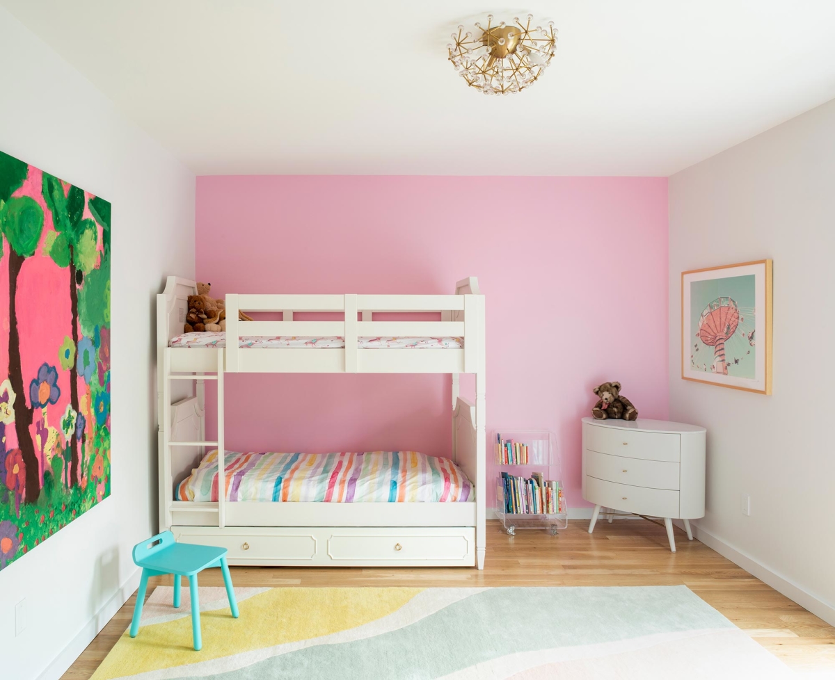 Jersey City Condo residential interior design by Basicspace. Pink girl's bedroom with large kid's art, flower ceiling light, rainbow rug and round dresser.