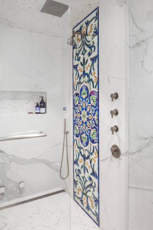 Park Slope Brownstone bathroom residential interior design renovation by Basicspace. Detail of colorful glass mosaic art inlay, with porcelain marble slabs and plumbing fixtures. Linear drain and shower niche, hand shower and recessed rain shower head complete the design.