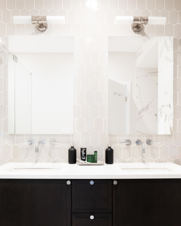 Jersey City Condo residential interior design by Basicspace. Master bathroom black and white double vanity, hexagon tile wall, wall-mounted faucets, medicine cabinet and sconces. 