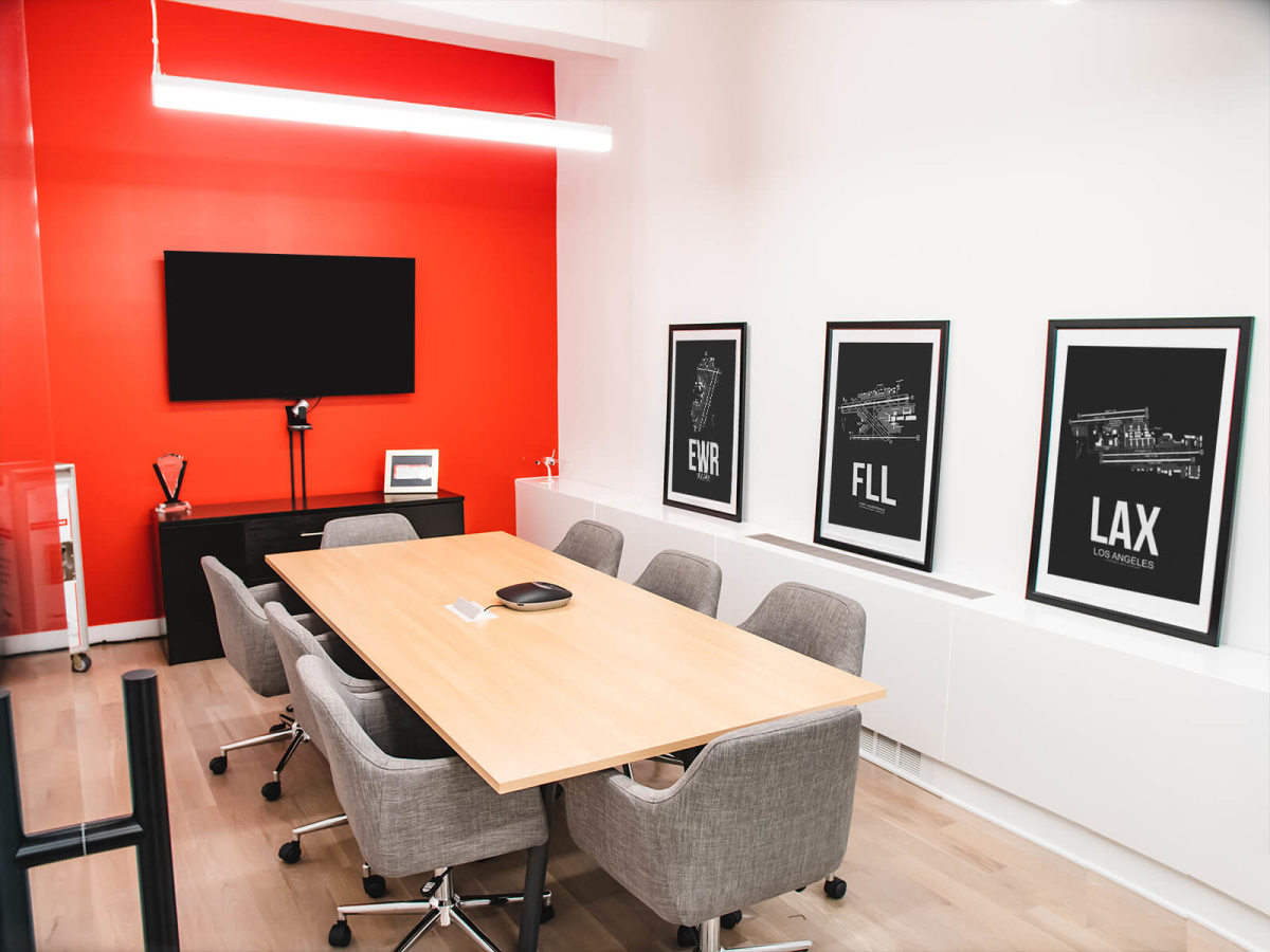 Norwegian Air office interior design by Basicspace. Display of conference room with vibrant Norwegian red accent wall with airport artwork displayed.