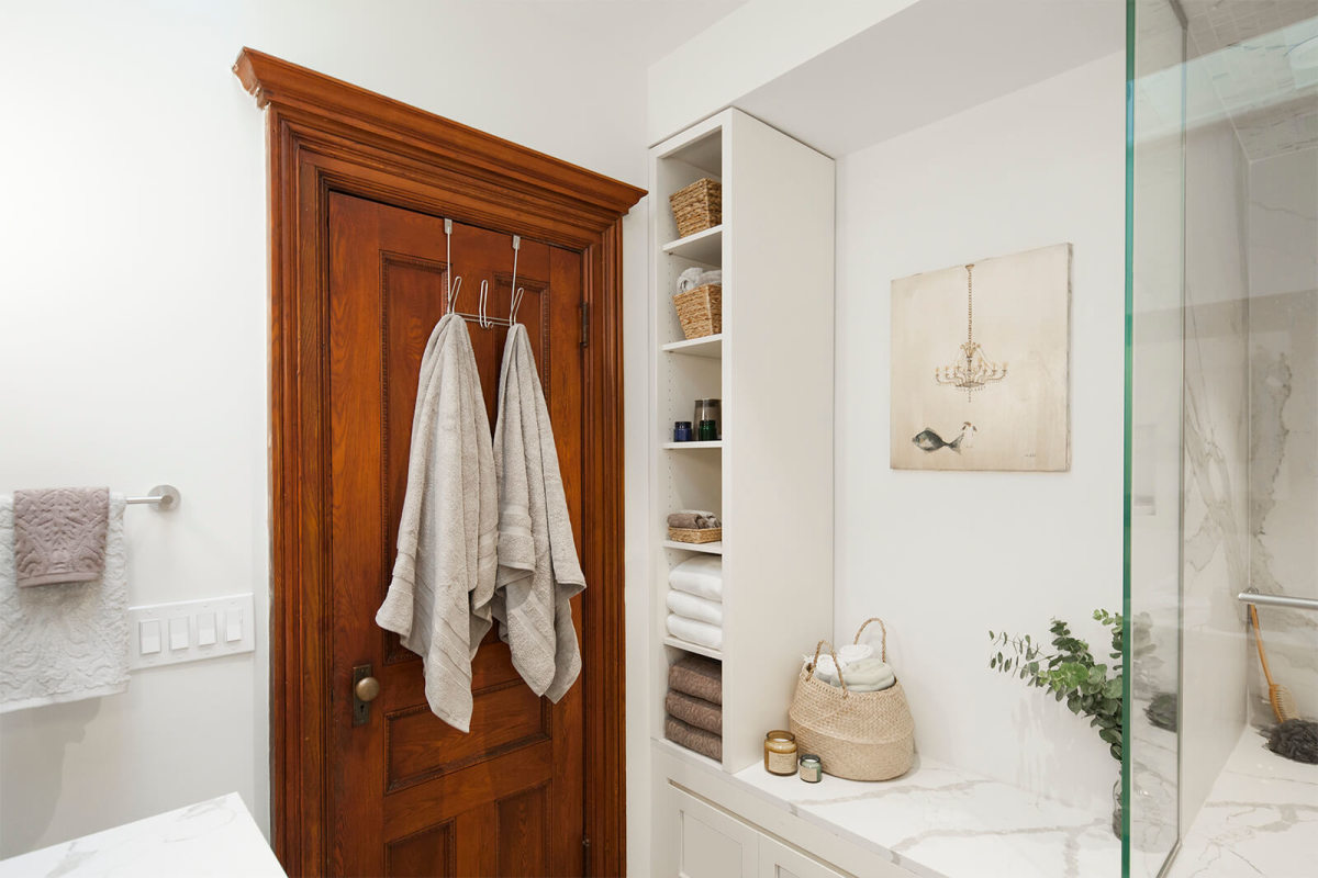 Park Slope Brownstone bathroom residential interior design renovation by Basicspace. Original solid wood door with new modern marble bench, custom millwork and open shelving.