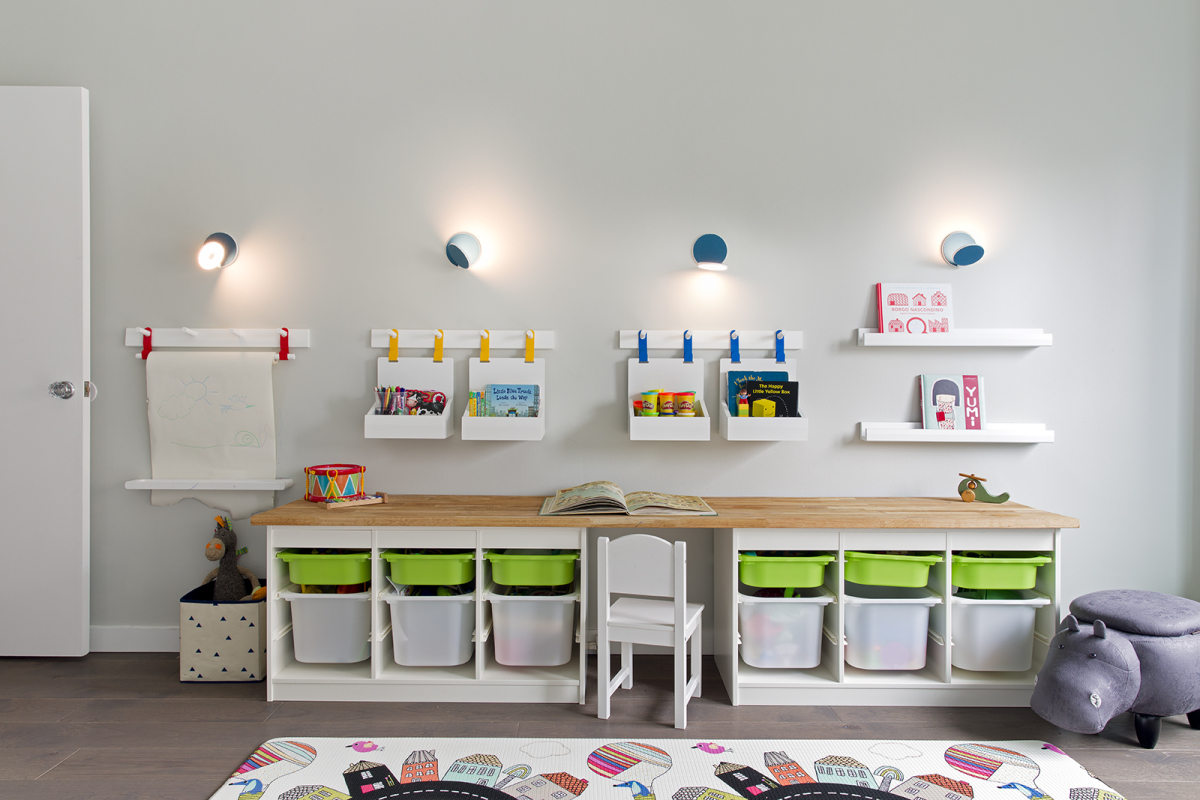 Lincoln Tower Apartment residential interior design renovation by Basicspace. Playful kids desk and wall storage with adjustable lighting. Art bins, baskets, shelving, and wall hooks for easy access to toys, arts and crafts, and books.