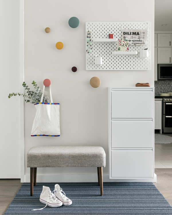 Lincoln Tower Apartment residential interior design renovation by Basicspace. Playful and welcoming entry foyer with polka dot coat hooks and wall mounted shoe storage and accessories organizer with small bench below.