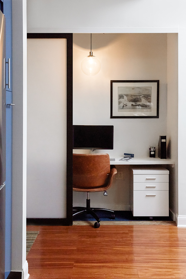 Hell's Kitchen Loft residential interior design by Basicspace. Hidden office behind sliding door panels in hallway.