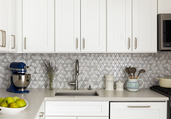 Lincoln Tower Apartment residential interior design renovation by Basicspace. Balanced triangular mosaic backsplash accenting white cabinets and light grey counters.