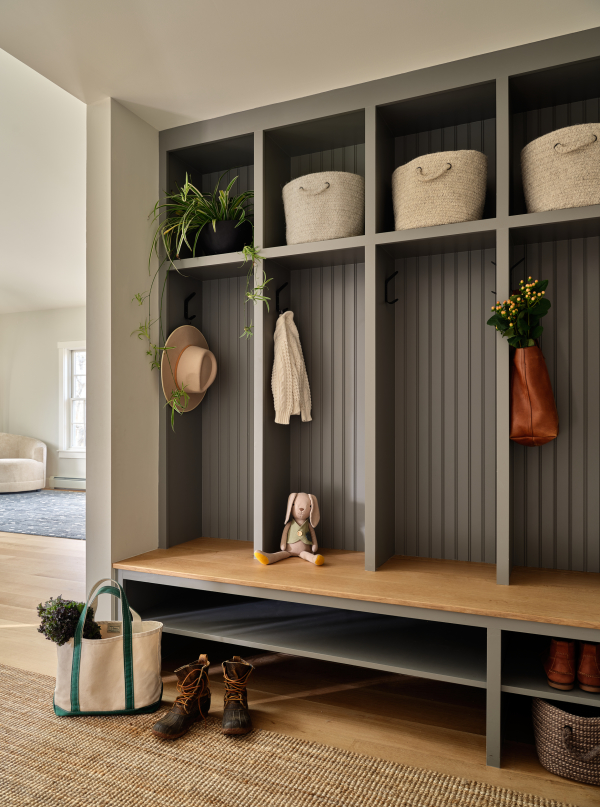 This custom built-in millwork completed the mudroom with dark beadboard paneling on the back of a cubby for each family member. Open shelving below provides shoe storage. The ultimate organized entry.