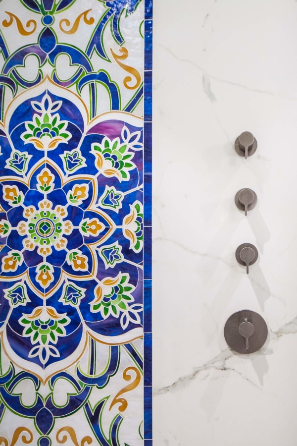 Park Slope Brownstone bathroom residential interior design renovation by Basicspace. Detail of colorful glass mosaic art inlay, with porcelain marble slabs and plumbing fixtures.