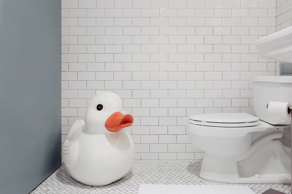 Hell's Kitchen Loft residential interior design by Basicspace. Detail of subway tile with an enlarged duck sculpture. Bathroom art.