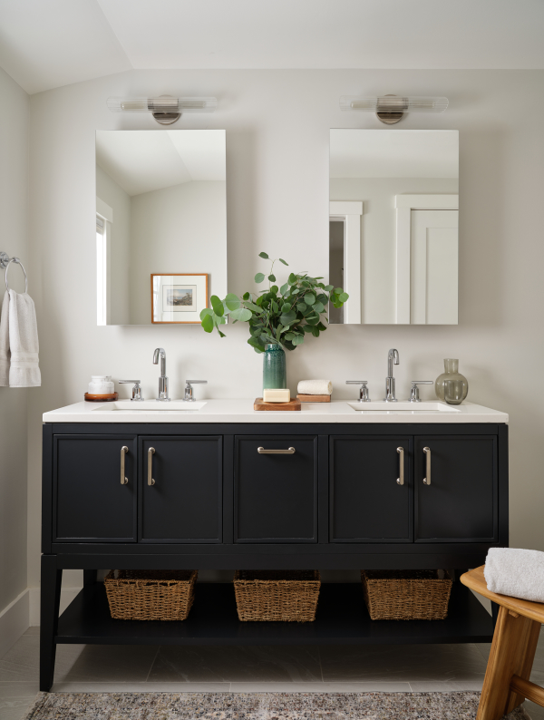 Polished chrome fixtures accent this double vanity with an open shelf below. Frameless mirrored medicine cabinets and modern sconce lights sit above the sinks.