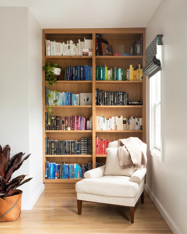 Jersey City Condo residential interior design by Basicspace. Color coded open bookcase shelving in reading nook.