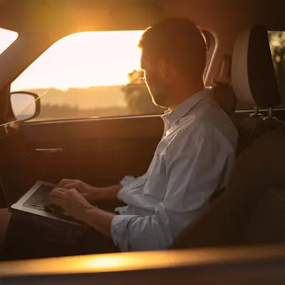 Un homme travaille sur un ordinateur portable dans sa voiture