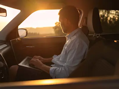 Un homme travaille sur un ordinateur portable dans sa voiture