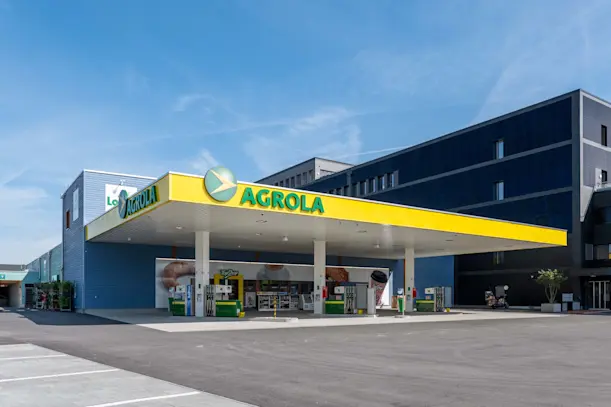 LANDI KoWy Aufnahme mit Dachband Tankstelle und mit PV eingekleideter Fassade. Am Himmel Kondensstreifen von Flugzeugen