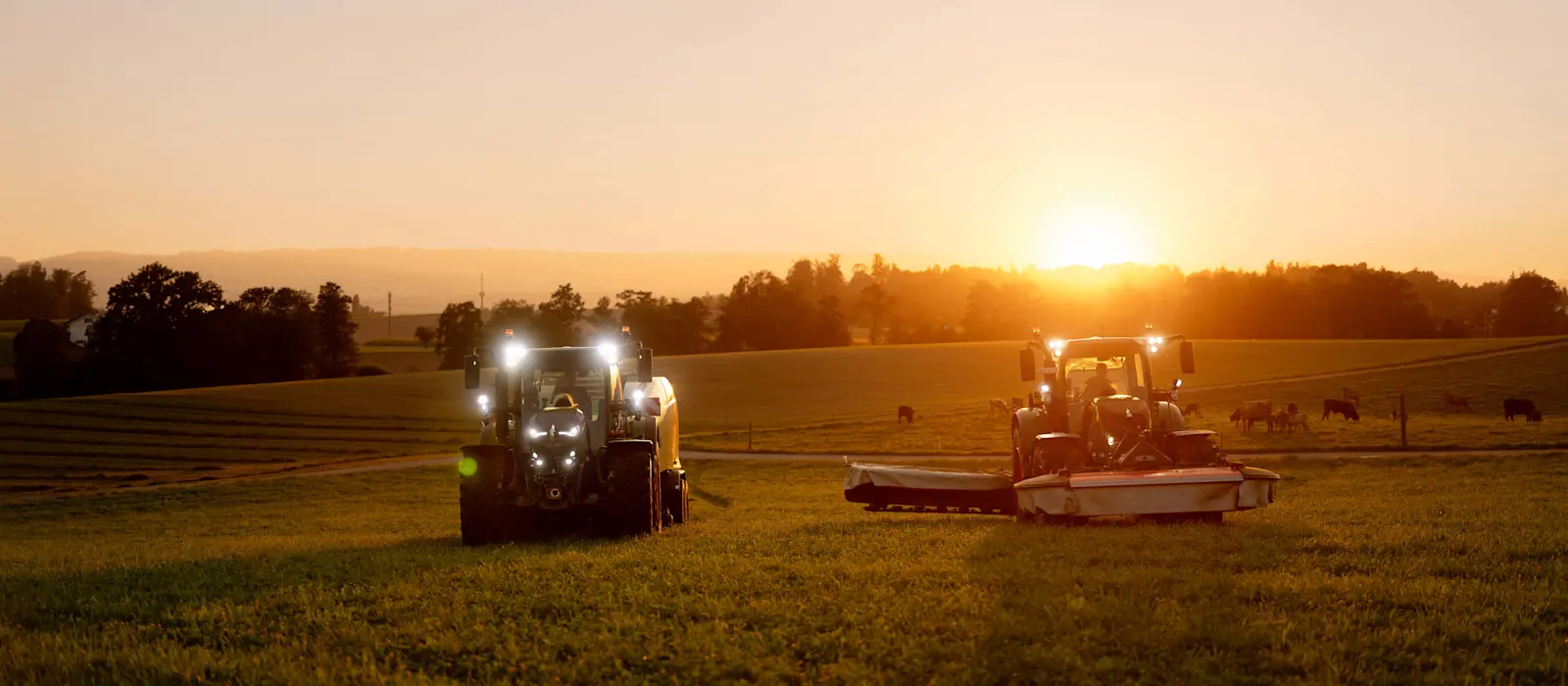 Tracteurs dans un champ au lever du soleil