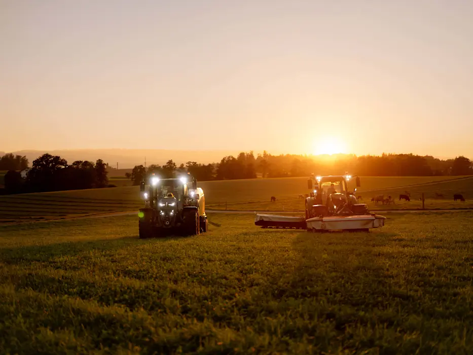 Tracteurs dans un champ au lever du soleil