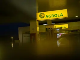 Vue d'une colonne de station-service AGROLA - éclairée avec les pistolets de distribution visibles.