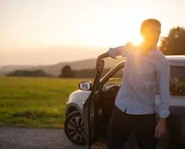 Bild Mobilität - Mann steigt aus Auto aus bei Sonnenaufgang
