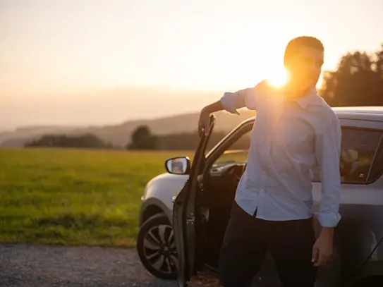 Bild Mobilität - Mann steigt aus Auto aus bei Sonnenaufgang