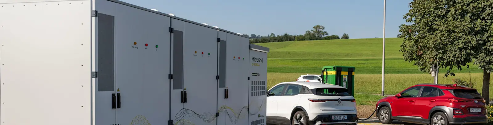 AGROLA MicroGrid und AGROLA Schnellladestation mit zwei Autos, die laden am Standort der LANDI Sursee in Oberkirch