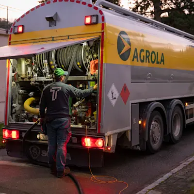 Le mazout AGROLA est livré, le chauffeur se tient devant le camion AGROLA avec le hayon arrière ouvert