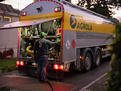 Le mazout AGROLA est livré, le chauffeur se tient devant le camion AGROLA avec le hayon arrière ouvert