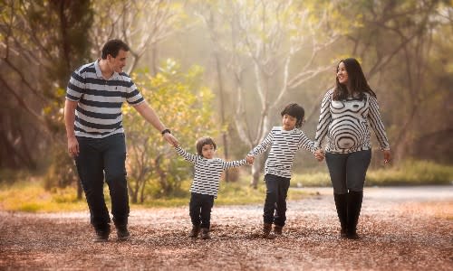 Happy family walking in the woods holding hands after successful IVF.
