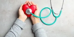 Woman holding red heart and stethoscope.