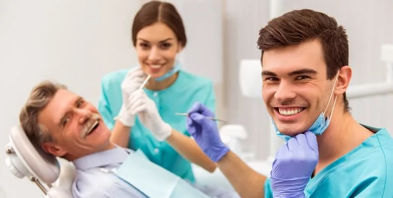 Patient und Zahnarzt lächeln nach dem Einsetzen von Zahnimplantaten