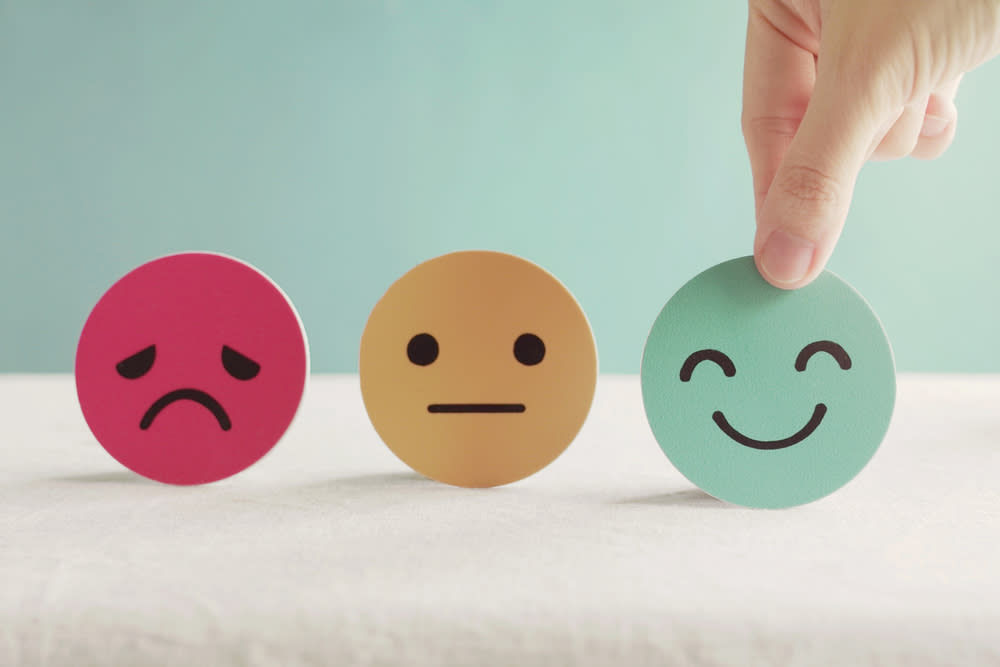 Picture of a person picking a happy face out of neutral and sad face 