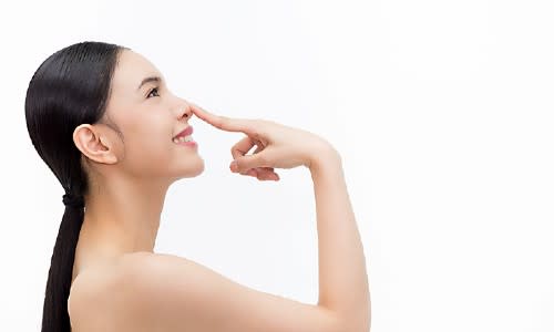 Happy woman touching her nose after rhinoplasty surgery.
