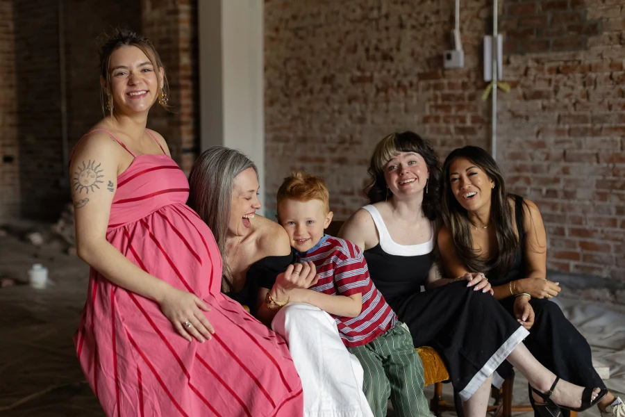 A seated group portrait with adults and a child inside The Den Family Social.